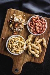 Unpeeled and peeled peanuts in bowl on kitchen table. Top view.