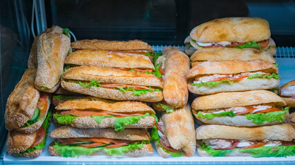 Assortment of sandwiches with lettuce, salmon, ham for sale on counter of market, cafe, store, shop or bakery. Take away, healthy, street, fast food concept