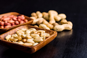 Unpeeled and peeled peanuts in bowl on kitchen table.