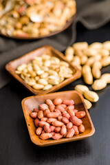 Unpeeled and peeled peanuts in bowl on kitchen table.