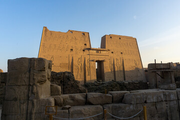 Exterior of the Edfu temple at dawn, with sunlight illuminating the main facade. - obrazy, fototapety, plakaty