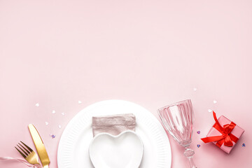 Table setting for Valentine's Day with gift on pink background
