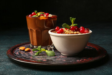 Plate with bowl and glass of delicious chocolate pudding, cranberry and almond on black table