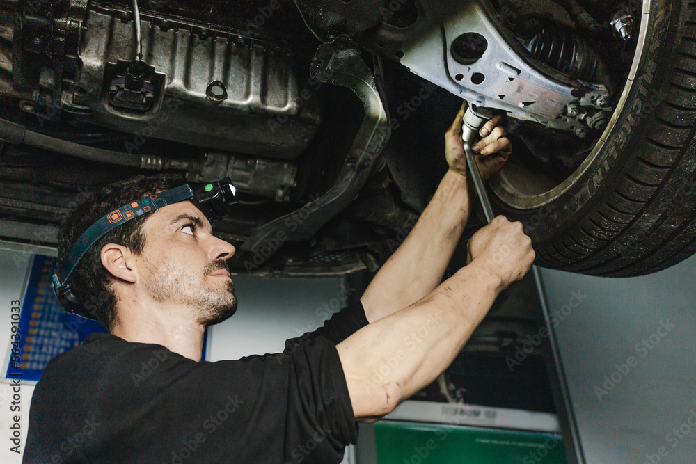 Wall mural Repairman installing car wheel in workshop