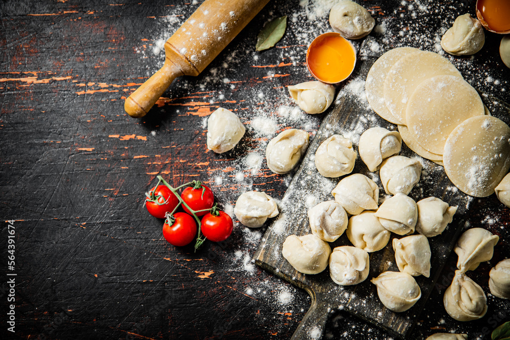 Wall mural Raw dumplings with flour, eggs and cherry tomatoes. 