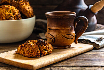 Homemade oatmeal cookies and prepared coffee in a ceramic dish on the kitchen table.