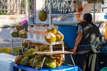  A food and drink vendor at an outdoor kiosk sells coconuts and coconut drinks at the Plaza...