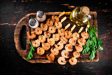 Grilled shrimp on skewers with parsley on a cutting board. 