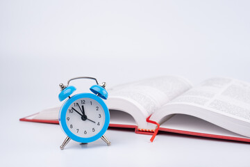 An Open Book Or Notebook And Blue Clock On The Table.	