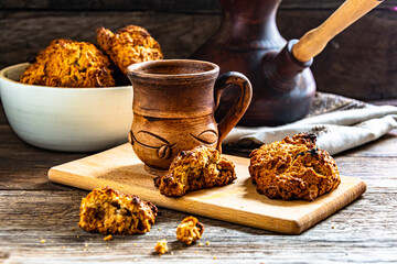 Homemade oatmeal cookies and prepared coffee in a ceramic dish on the kitchen table.