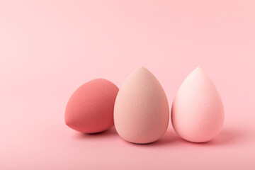 Colorful bright beauty sponges on a pink background. Beauty concept. Cosmetic tool for applying and blending and applying foundation, concealer. Copy space for text.