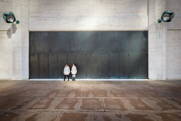 Two asian girls dressed in winter clothe standing in front of large doors