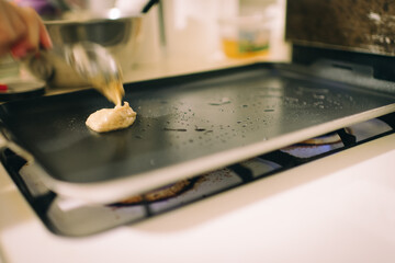 Young asian girl baking almond dollar size pancake for her father