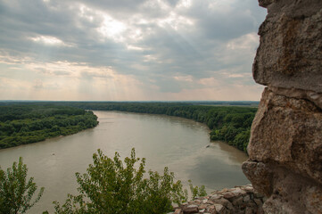 Obraz premium Looking out a window from Devin Castle towards a wide river with sunlight beaming through the clouds in Bratislava, Slovakia