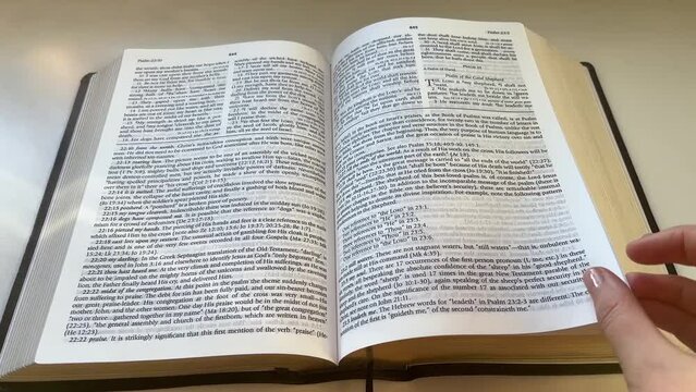 Point of view slow motion shot of reading of a thick study Bible Psalm 23 and 24; fingers turning a page