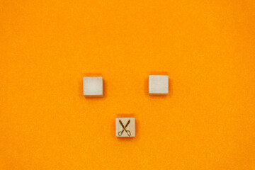 ハサミによって分けられた2つのウッドキューブのオレンジ色の背景