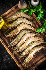 Raw shrimp on a cutting board with spices and parsley. 