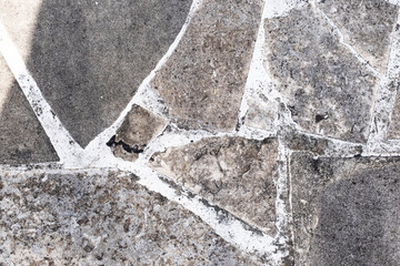 Pieces of broken flat stones set in white cement pavement. Background and wallpaper texture