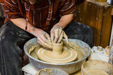 Professional male potter making ceramics on pottery wheel in workshop, studio. Close up view of potter hands. Handmade, art and handicraft concept