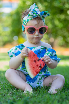 Portrait of fashionable little girl eating watermelon slice outdoors.