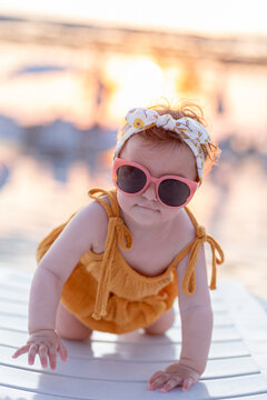 Cute baby girl with sunglasses on sunbed during summer vacation.