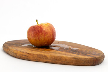 Red apple on wooden chopping board on white background isolated