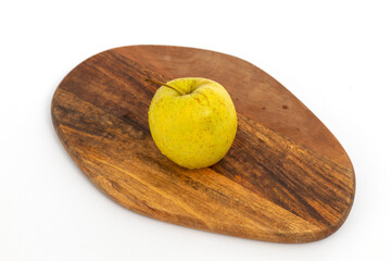 Yellow apple on wooden chopping board on white background isolated
