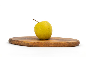 Yellow apple on wooden chopping board on white background isolated