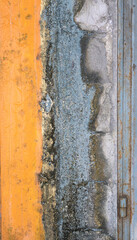 Dilapidated light orange painted concrete wall with blue cement and plaster. Background texture
