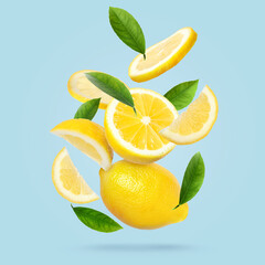 Fresh ripe lemons and green leaves falling on pale light blue background