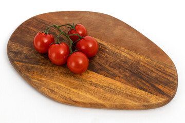 Cherry tomatoes on wooden chopping board on white background isolated
