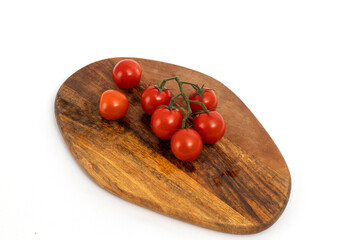 Cherry tomatoes on wooden chopping board on white background isolated