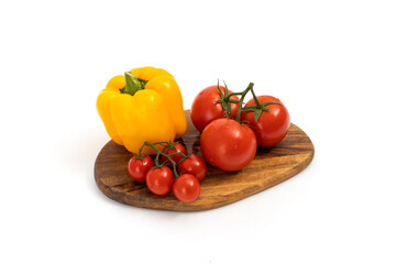 Yellow pepper and cherry tomatoes on wooden chopping board on white background isolated