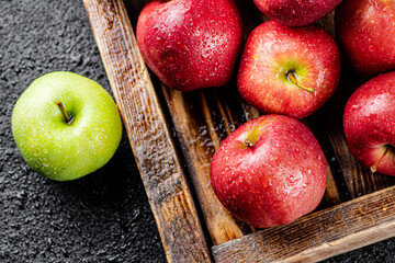 Red apples on a wooden tray with one green apple. 