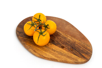 Yellow cherry tomatoes on wooden chopping board on white background isolated