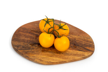 Yellow cherry tomatoes on wooden chopping board on white background isolated