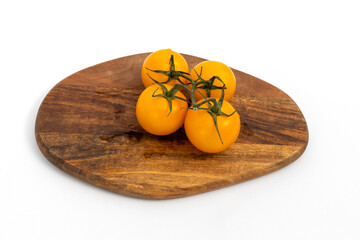 Yellow cherry tomatoes on wooden chopping board on white background isolated