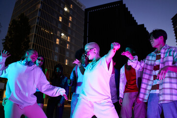 Young People dancing at party night in the city. Modern multicultural friends enjoying music together. High quality photo