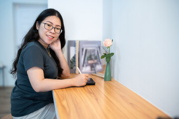 Portrait asian freelance people business female wearing glasses stylish hipster Draw or taking note on digital tablet with electronic pen for browsing internet, chatting and blogging in coffee shop.