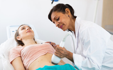 Fototapeta premium Portrait of female doctor performing electroporation mesotherapy body treatment to woman at aesthetic clinic