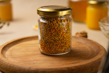 Bee pollen in a glass jar with honey in the background
