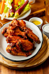 
Chicken wings. Buffalo chicken wings. American cuisine of chicken wings deep-fried, dipped in buffalo sauce made of vinegar,  cayenne hot sauce and butter. Served with celery, carrots, blue cheese.