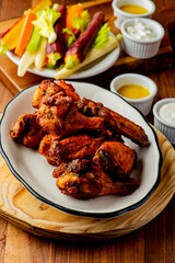 
Chicken wings. Buffalo chicken wings. American cuisine of chicken wings deep-fried, dipped in buffalo sauce made of vinegar,  cayenne hot sauce and butter. Served with celery, carrots, blue cheese.