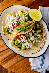Tacos. Crispy flour and corn tortillas filled with sausage, bacon, beef, cheese, sour cream, salsa and guacamole and served with rice and beans. Classic Tex-Mex or Mexican restaurant entrée favorite.