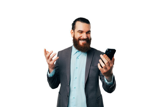 Handsome bearded man wearing jacket is talking on speaker over the phone.