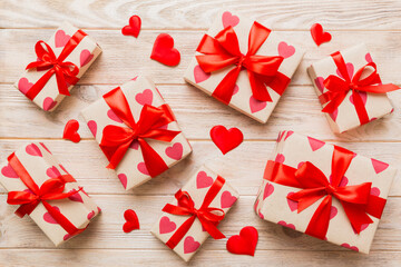 Top view photo of valentine day decorations gift box with red ribbon bow on colored background....