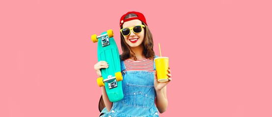 Portrait of happy smiling young woman with skateboard and cup of juice wearing red baseball cap,...