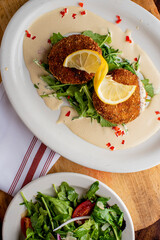 Crab cake. Crab cake served with spicy rémoulade sauce on top of a mixed green salad. Jumbo crab meat mixed with garlic, onions, spices and fried in butter. Classic American restaurant appetizer.