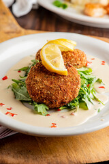 Crab cake. Crab cake served with spicy rémoulade sauce on top of a mixed green salad. Jumbo crab meat mixed with garlic, onions, spices and fried in butter. Classic American restaurant appetizer.
