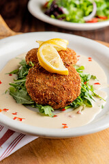 Crab cake. Crab cake served with spicy r&eacute;moulade sauce on top of a mixed green salad. Jumbo crab meat mixed with garlic, onions, spices and fried in butter. Classic American restaurant appetizer.